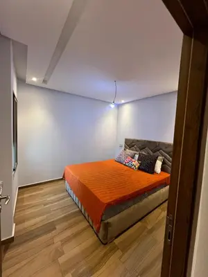 a bedroom with a bed with an orange blanket at Blue beach Sidi Rahal in Le Polo