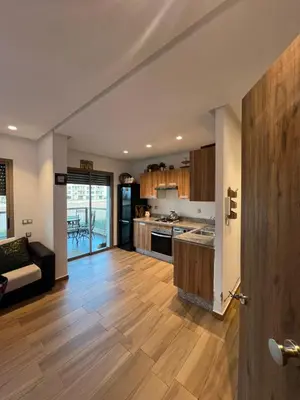 a large kitchen with wooden floors and a living room at Blue beach Sidi Rahal in Le Polo