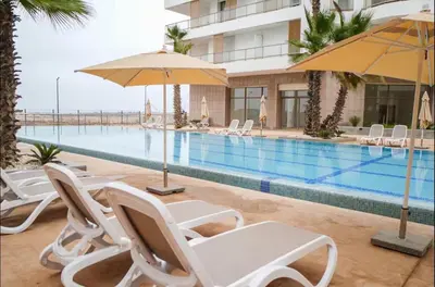 a swimming pool with chairs and umbrellas next to a building at Ocean Pearl Luxury Stay by Sea in Casablanca