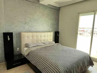 a bedroom with a bed with a striped comforter and a window at Appt Centre ville Casablanca Maarif avec Terrasse in Casablanca