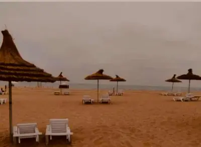 a group of chairs and umbrellas on a beach at Blanca beach in Sidi Rahal