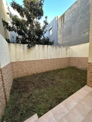 a brick fence with a tree in front of a building at Beautiful villa Near the beach in Mohammedia