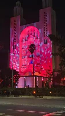 a building is lit up in pink at night at Apartment with terrace - Strategic location in Casablanca