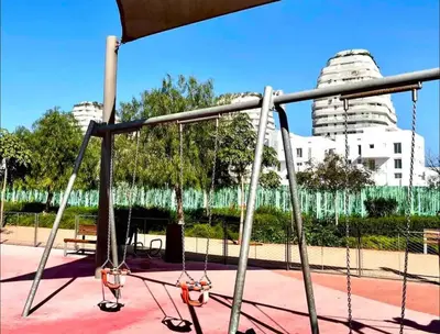 a swing set in a park with buildings in the background at Sunshine Apartment in Casablanca