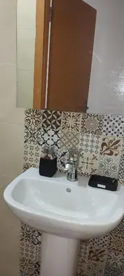 a white sink in a bathroom with a mirror at Logement cozy in Oulad Kerroum