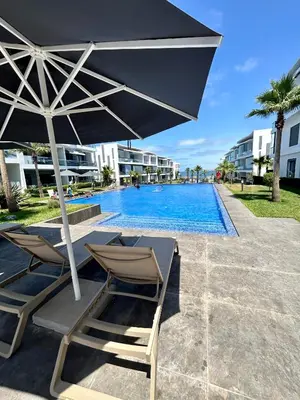 a pair of chairs and an umbrella next to a swimming pool at Condo beach view in Casablanca in Casablanca