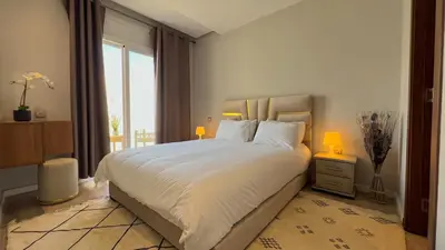 a bedroom with a large white bed with two lamps at N42 Luxe et Élégance avec Jacuzzi Privatif sur la Corniche Rabat Essabah in Rabat