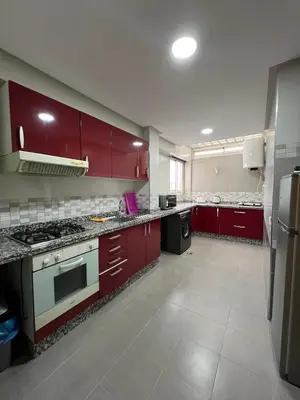 a large kitchen with red cabinets and appliances at SUITOUISS - AGDAL 5 - Appartements à 2 minutes de la gare de train TGV Rabat in Rabat