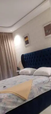 a bed with a blue headboard in a bedroom at AbboGroup APPARTEMENT in Casablanca