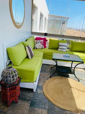 a living room with a green couch and a table at Sidi rahal blue beach Cozy apartment with a sea view in Sidi Rahal