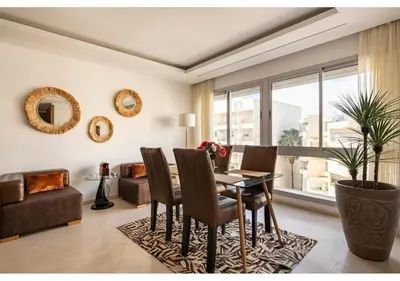 a dining room with a table and chairs and a couch at Cosy cocon urbain 34 in Rabat
