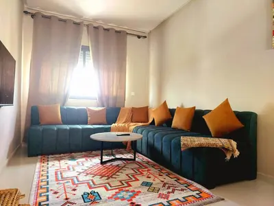 a living room with a blue couch and a table at Family airport relax apartment in Deroua