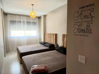 a bedroom with two beds and a sign on the wall at Family airport relax apartment in Deroua