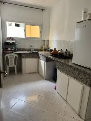 a kitchen with granite counter tops and a white refrigerator at Appartement Dadi in Rabat