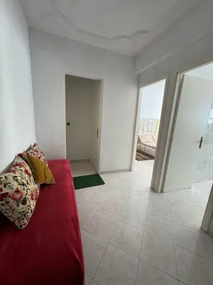 a living room with a red couch and a large window at Appartement Dadi in Rabat