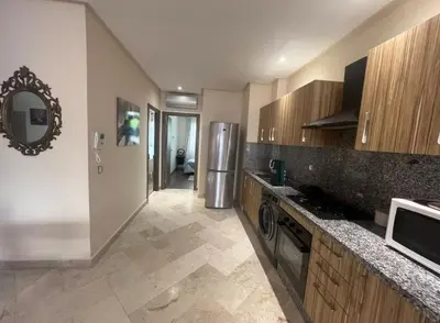 a kitchen with wooden cabinets and a counter top at Neuf 3min de la plage au parc avec parking in Mohammedia