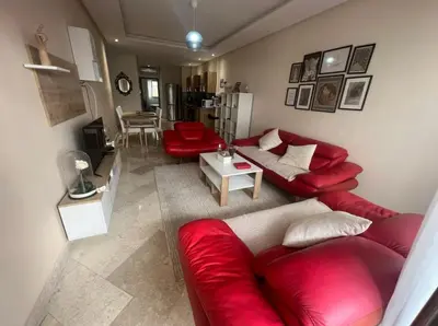 a living room with a red couch and red chairs at Neuf 3min de la plage au parc avec parking in Mohammedia