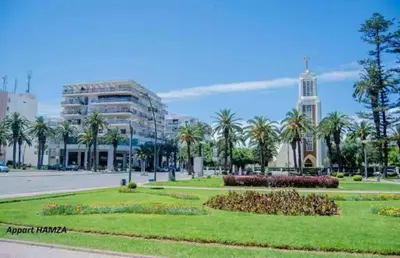 a park with palm trees and a building at Neuf 3min de la plage au parc avec parking in Mohammedia