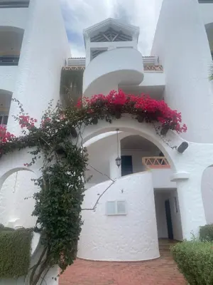 a white building with flowers on the side of it at Appartement balnéaire équipé in Sidi Rahal