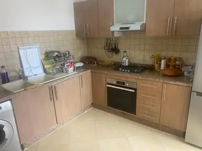 a kitchen with wooden cabinets and a stove top oven at Appartement balnéaire équipé in Sidi Rahal