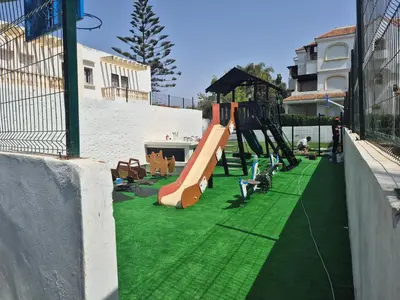 a playground with a slide on a green lawn at Appartement balnéaire équipé in Sidi Rahal
