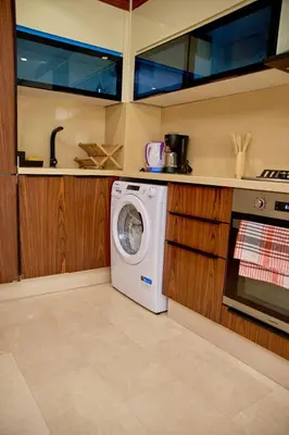 a washing machine in a kitchen with wooden cabinets at Les Princesse superbe Studio neuf moderne in Casablanca