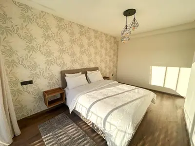 a bedroom with a bed with white sheets and floral wallpaper at Appartement luxueux 2 Chambres avec salle de sport et parking in Casablanca