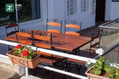 a wooden table and chairs on a porch with plants at Beachside Retreat Rabat - Zayane Homes in Temara