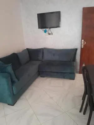 a living room with a green couch and a flat screen tv at Dahomy bouzni9a in Bouznika