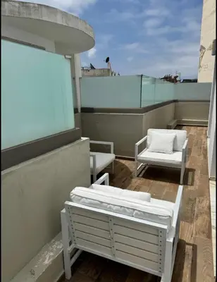 a balcony with two beds and two chairs on a roof at Résidence Saphir Luxury apartment with terrace in Racine in Casablanca