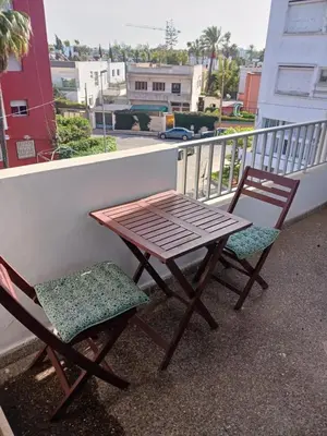a wooden table and two chairs sitting on a balcony at Spacious Apartment In CIL Casablanca in Casablanca