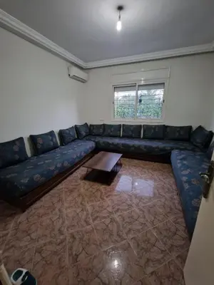 a living room with a blue couch and a table at Villa spacieuse avec piscine proche aéroport Mohamed V in Nouaseur