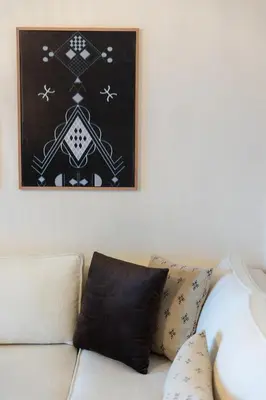 a couch with two pillows sitting under a picture at Prestige Penthouse Style and Serenity Rabat by MERAT HOME in Rabat