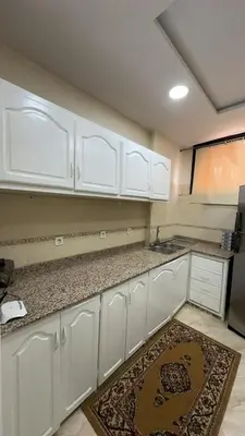 a kitchen with white cabinets and a rug on the floor at Spacious apartment in Settat