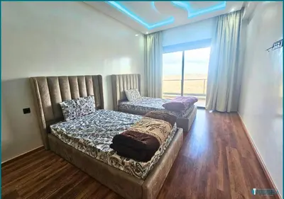 a bedroom with two beds and a large window at Une petite parenthèse marine in Mansouria