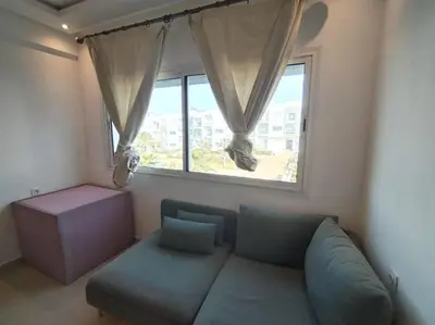 a living room with a couch and a window at Sunny apartment in El Harhoura