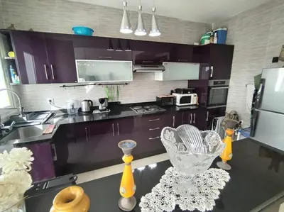 a kitchen with purple cabinets and a black counter top at Sunny apartment in El Harhoura