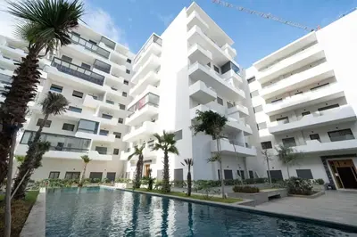 an apartment building with a swimming pool and palm trees at Nice & Comfortable 2BHK panoramic balcony with swimming pool in Aïn Harrouda