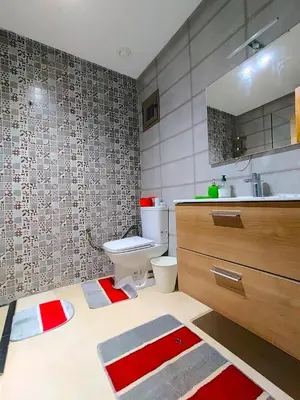 a bathroom with a toilet and a sink with red and white rugs at Joli appartement au centre-ville de Rabat in Rabat
