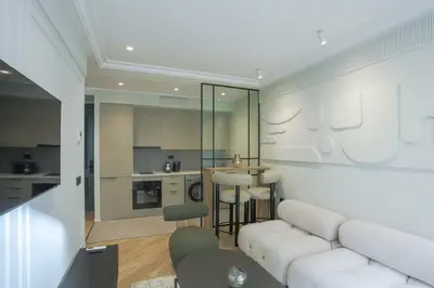a living room with a white couch and a kitchen at Résidence Claridge Racine in Casablanca