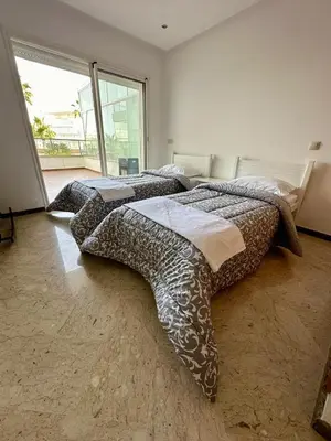 two beds in a room with a large window at Peninsula Dar Bouazza in Tamaris