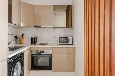 a small kitchen with a microwave and a washer at Appartement de luxe - Les Princesses avec Parking in Casablanca