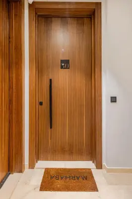 a wooden door with a mat in front of it at Appartement de luxe - Les Princesses avec Parking in Casablanca