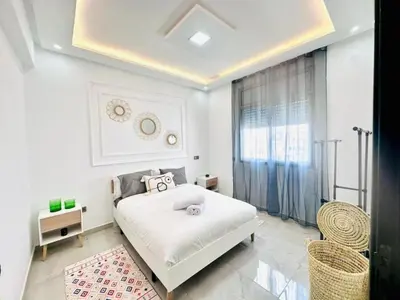 a white bedroom with a bed and a window at Elegant 3BR Stay 5min to Hay Riad in Temara