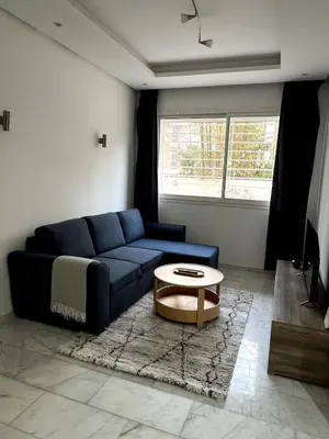 a living room with a blue couch and a coffee table at 1 bed apt In Prestigia hay Riad rabat in Rabat