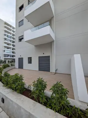 a white building with plants in front of it at Appt neuf Zenata- 2 chambres et Mezzanine - Piscine in Aïn Harrouda