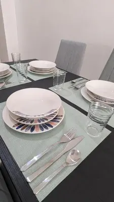a black table with white plates and silverware on it at Appt neuf Zenata- 2 chambres et Mezzanine - Piscine in Aïn Harrouda