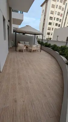 a patio with a table and chairs and an umbrella at Appt neuf Zenata- 2 chambres et Mezzanine - Piscine in Aïn Harrouda