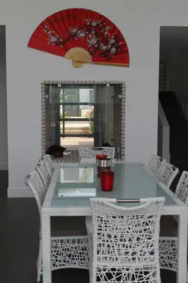 a dining room table with white chairs and a red umbrella at Eden Island Villa - Bouznika in Bouznika