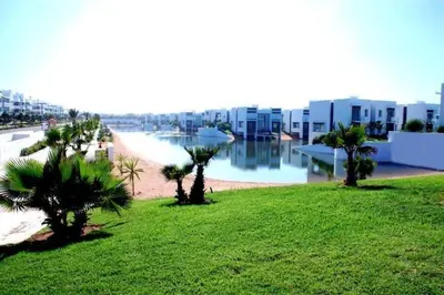 a view of a beach with palm trees and buildings at Eden Island Villa - Bouznika in Bouznika